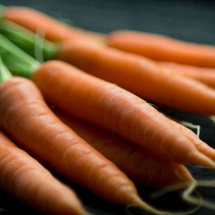 A bunch of carrots with leaves sitting on a black table