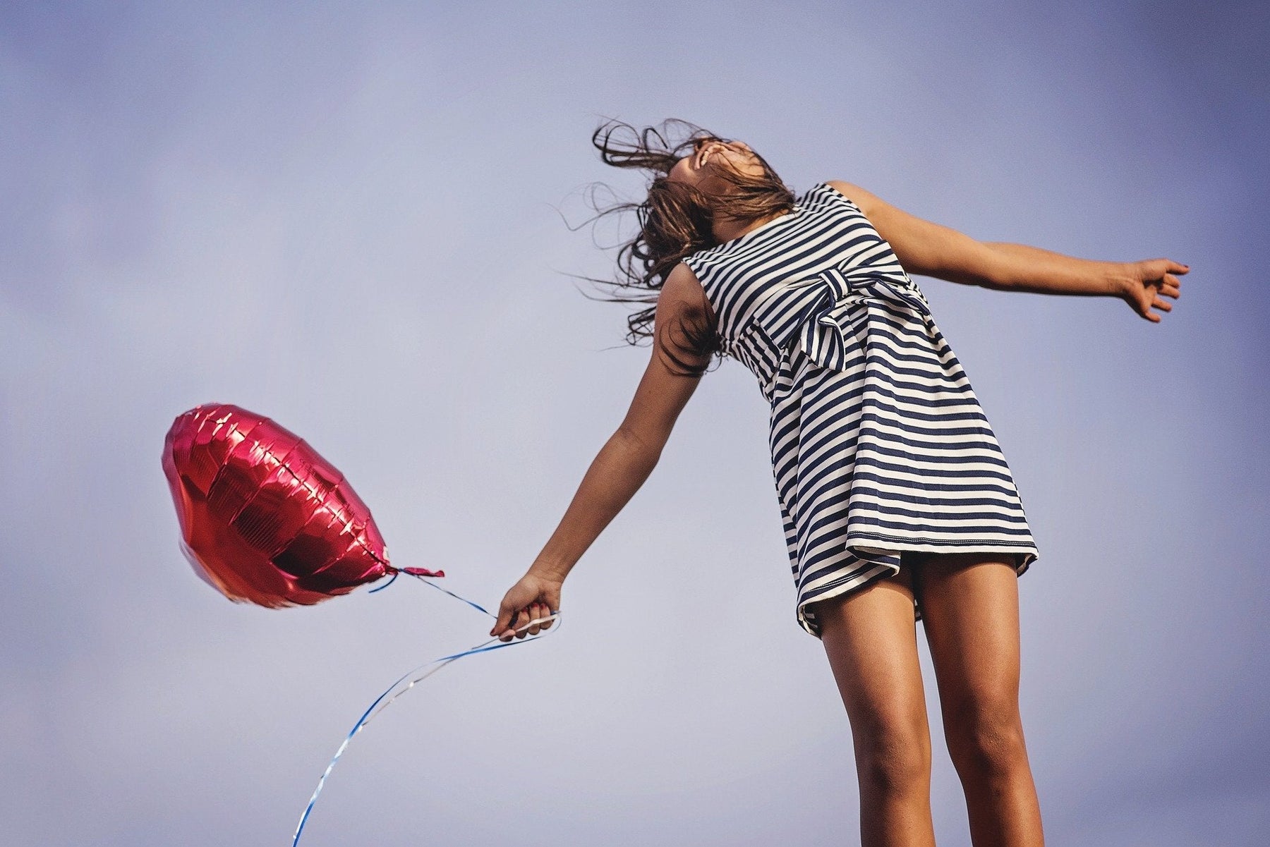 Happy girl in dress holding a red balloon