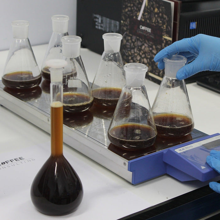 Person with gloves handling glass recipients with black liquid