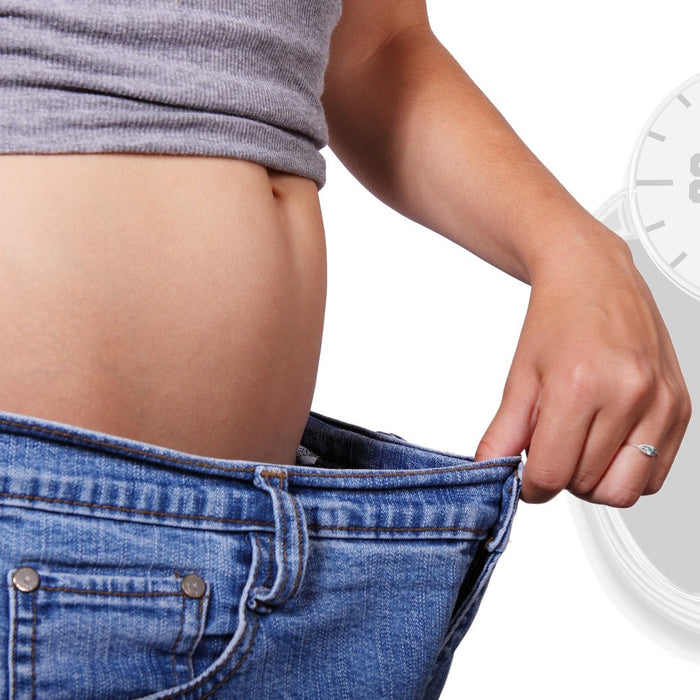 Woman wearing oversized jeans expressing weight loss