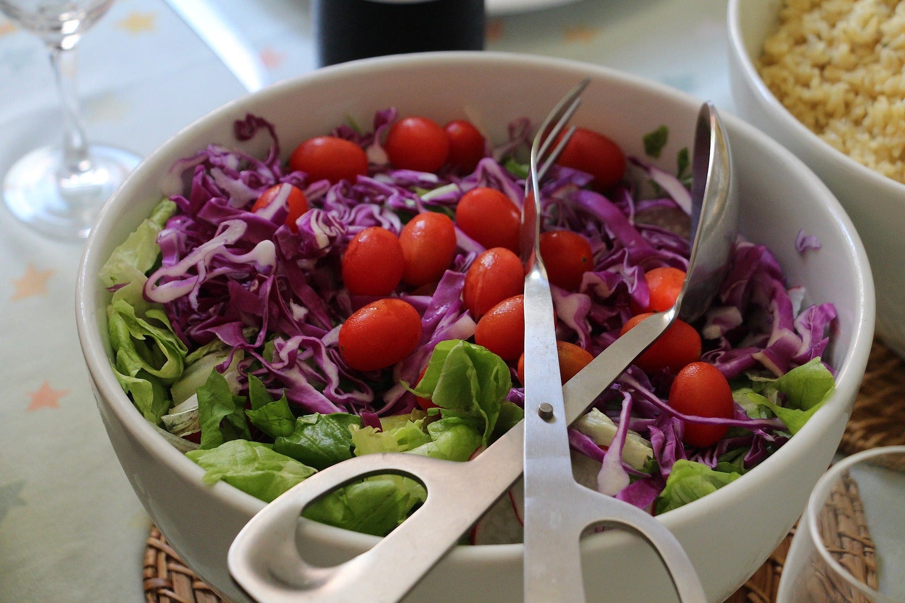 Salad with tomatoes sitting in a white bowl with a special salad claw