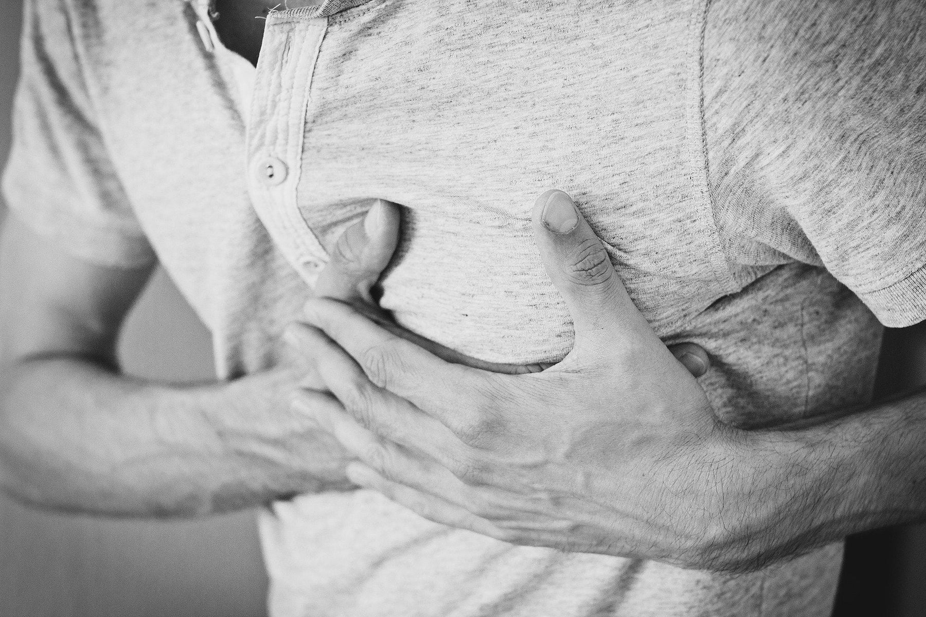 Man in t-shirt holding his chest in pain with both hands