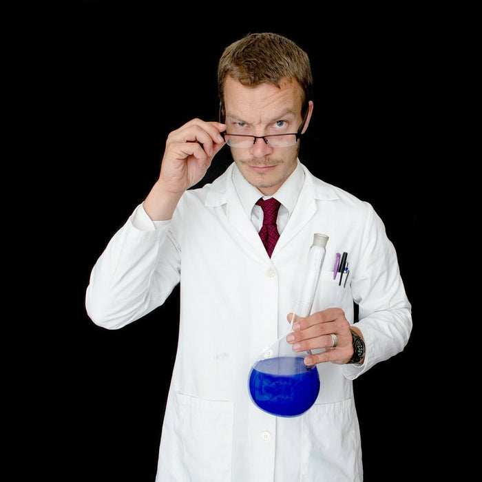 Laboratory man holding his glasses and a glass recipient with blue liquid