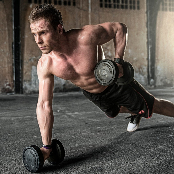 Shirtless man exercises with dumbells from pushup position