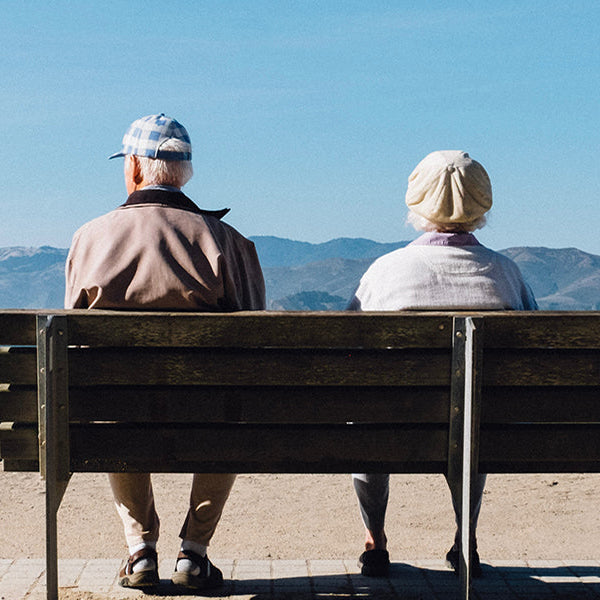 Old woman and old man sitting on a bench watching the mountain
