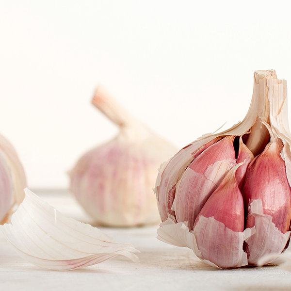 Three pieces of garlic slightly pilled on a white surface