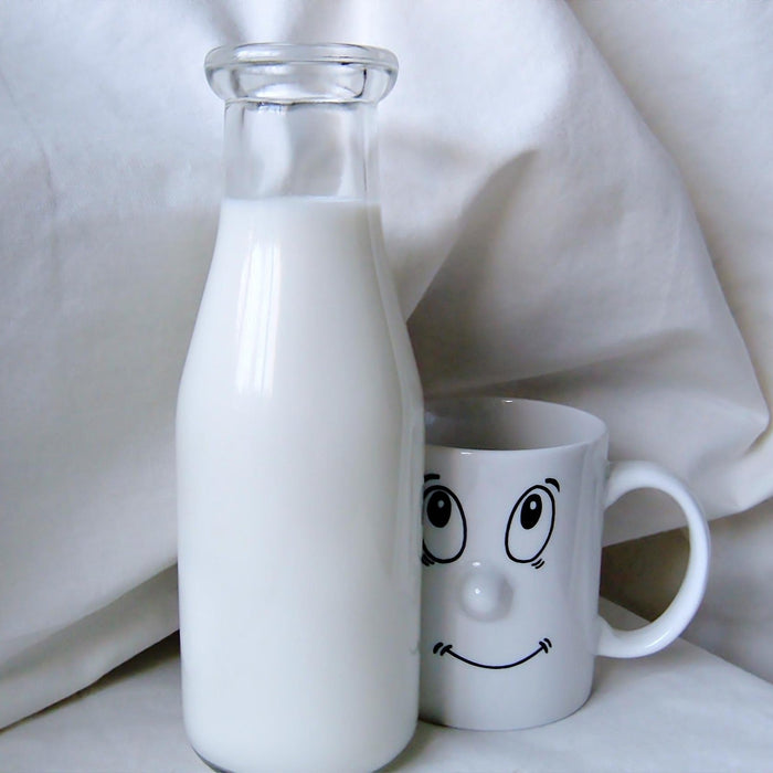 Bottle of milk next to a cup with a face drawn on it