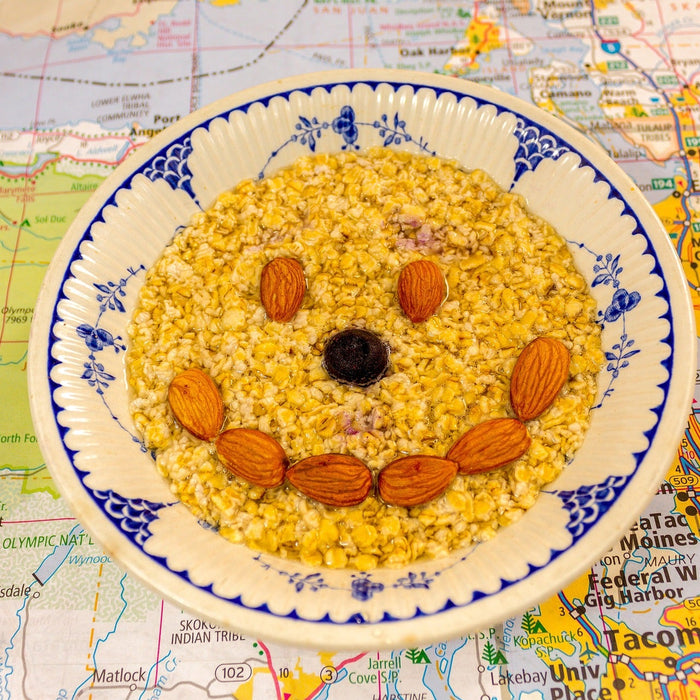 A bowl of outmeal with a smiley face made from almonds