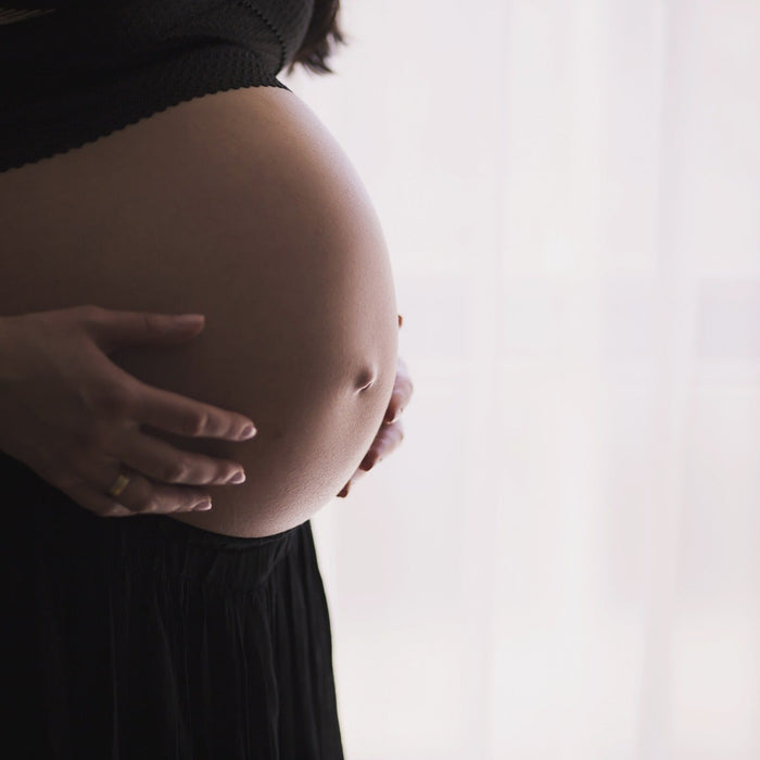 Pregnant woman wearing black with hands over the belly