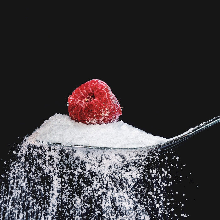 Raspberry above a pile of sugar held by a spoon
