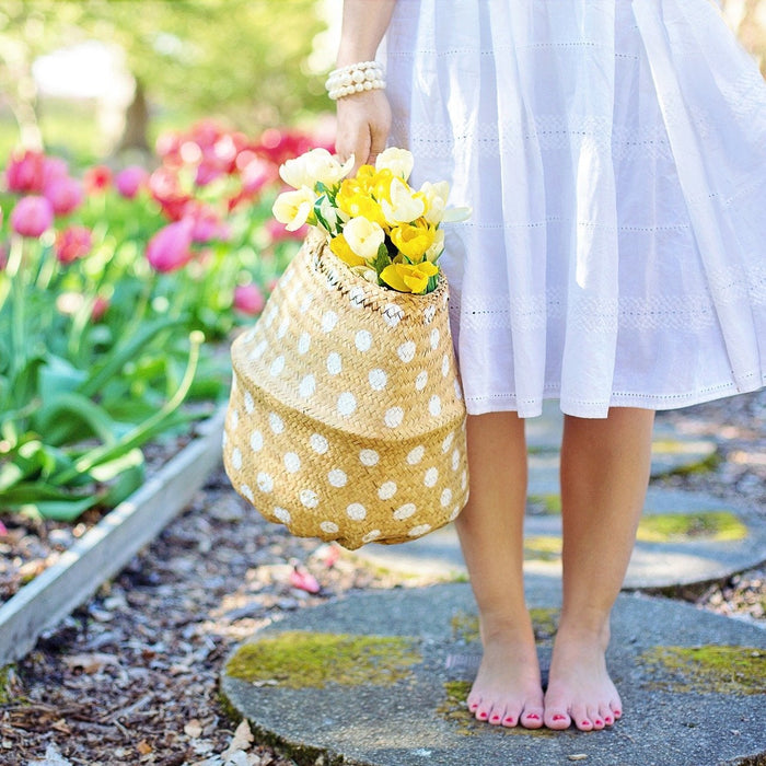 Girl in a white dress sitting on a piece of stone, surrounded by a garden of flowers