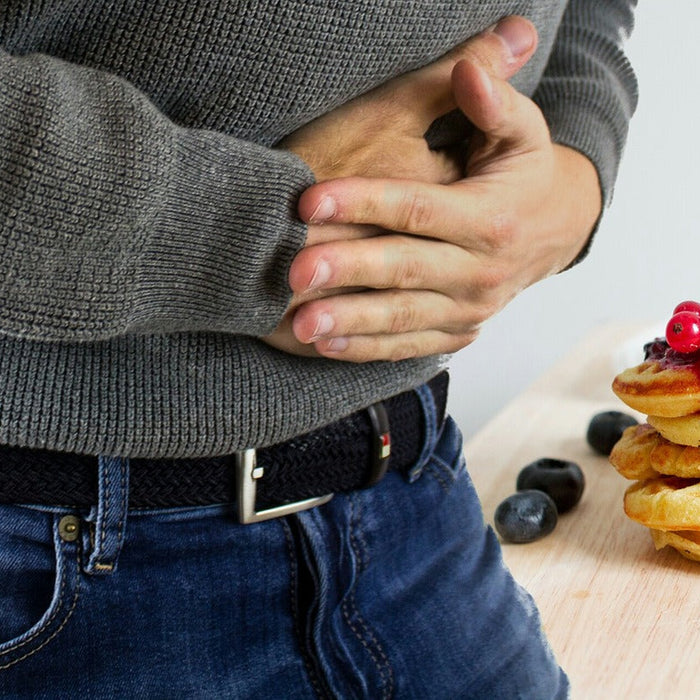 Man in sweater and jeans expressing stomach pain