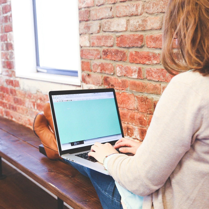 Woman sitting on a wooden bench working on a laptop