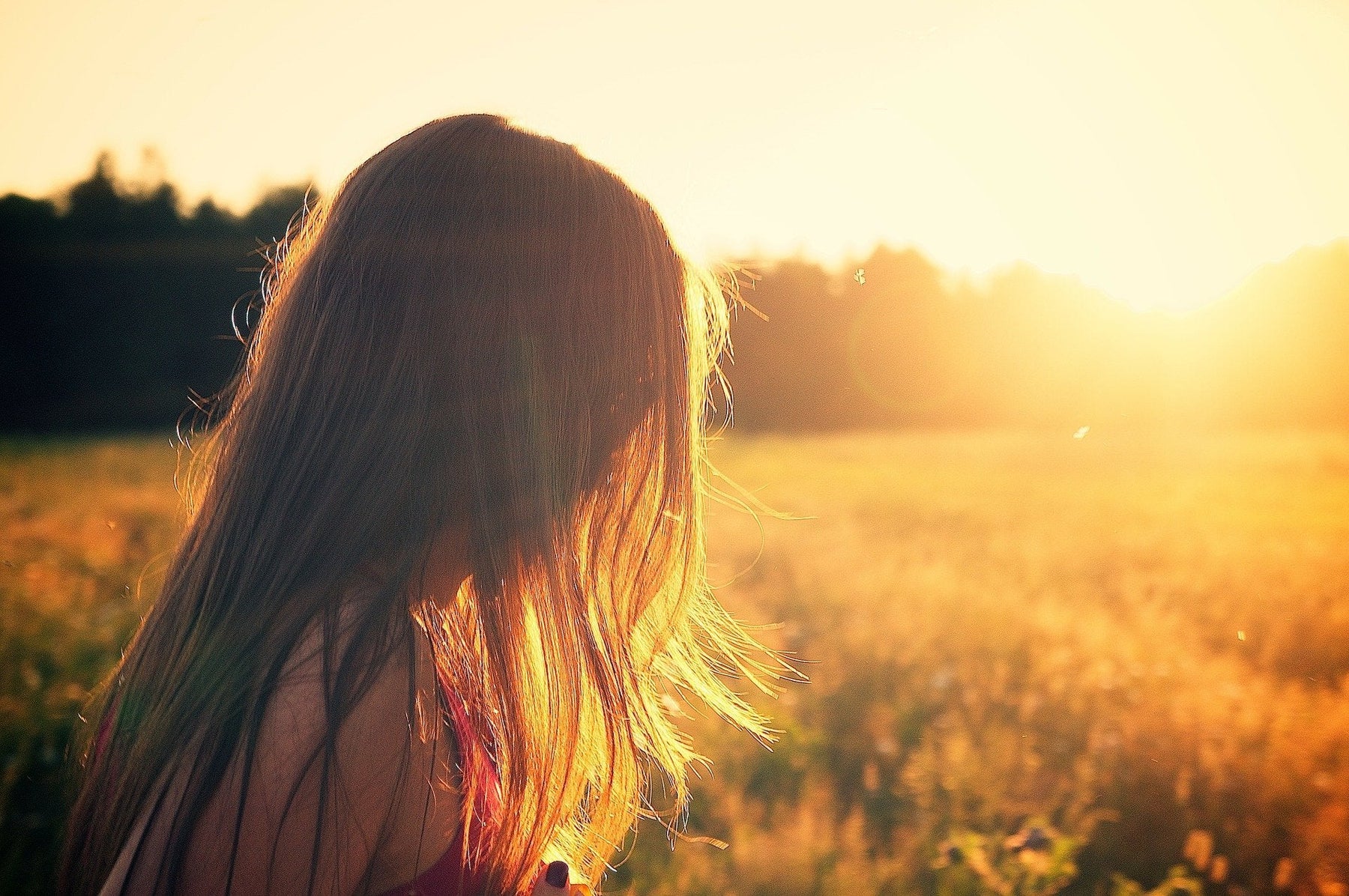 Woman facing a sunrise over a field