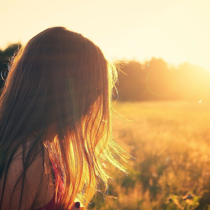 Woman facing a sunrise over a field