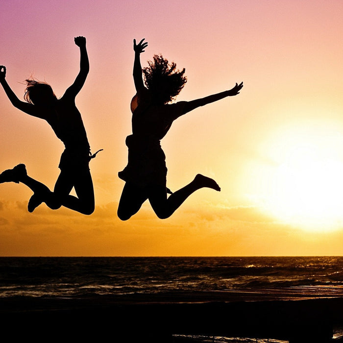 Women jumping at a sunset over the beach
