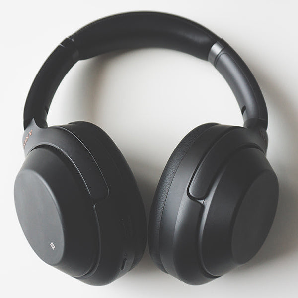 Black headphones on a white table next to a white mouse and keyboard