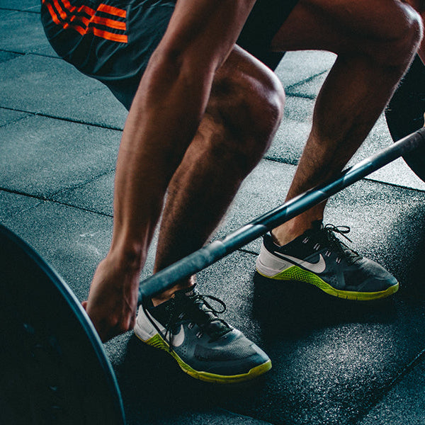 Man preparing to lift a barbell sitting on a black floor
