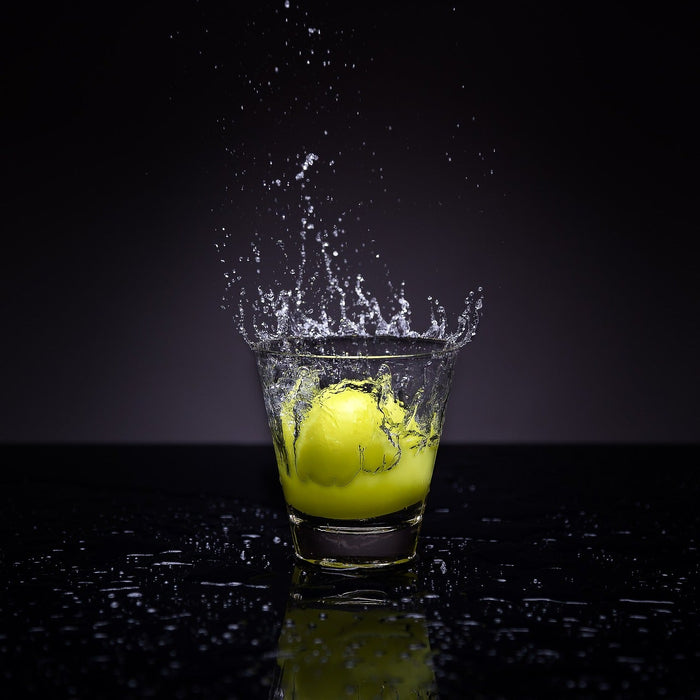 Lemon thrown in a glass of water over a black background