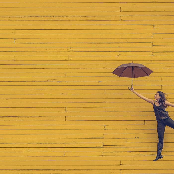 Woman holding umbrella with a foot pointed slightly up