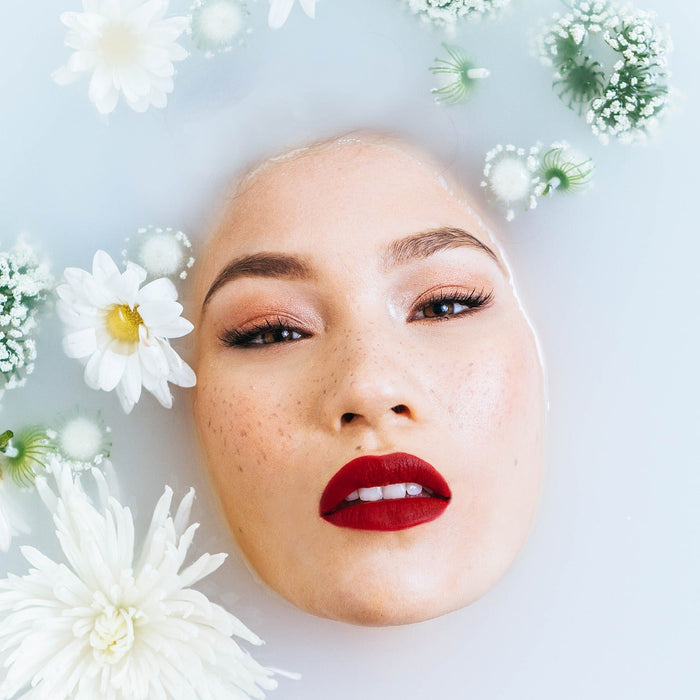Woman with red lips covered by water and plants