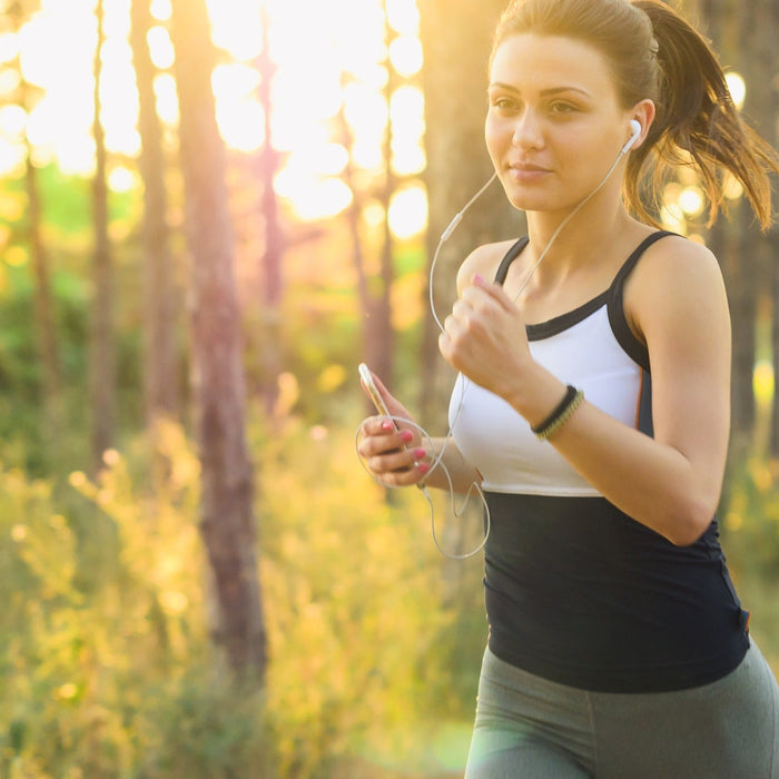 Woman listening to headphones running through woods