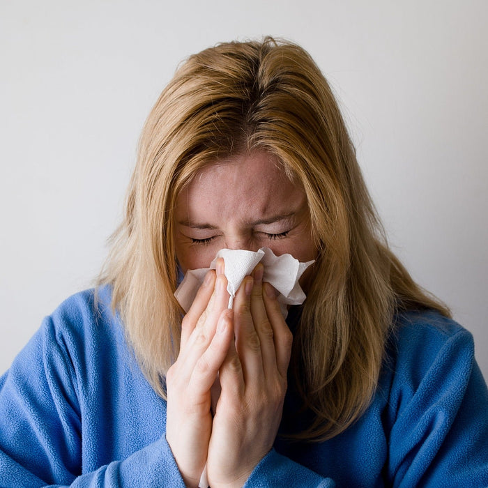 Woman dressed in blue blowing her nose
