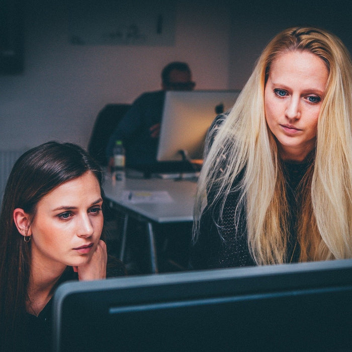 A brunette woman and a blonde woman looking at a screen in an office