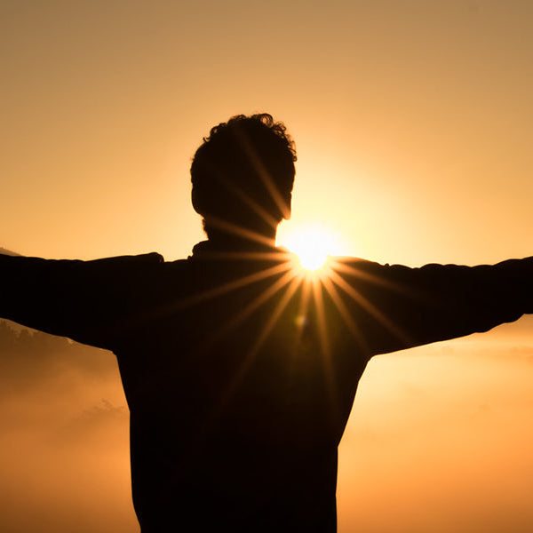 Man enjoying sunset with hand raised